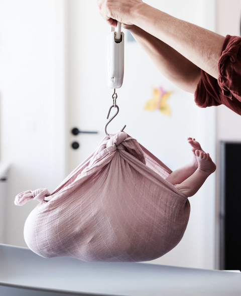 baby i slynge bliver vejet af sundhedsplejerske